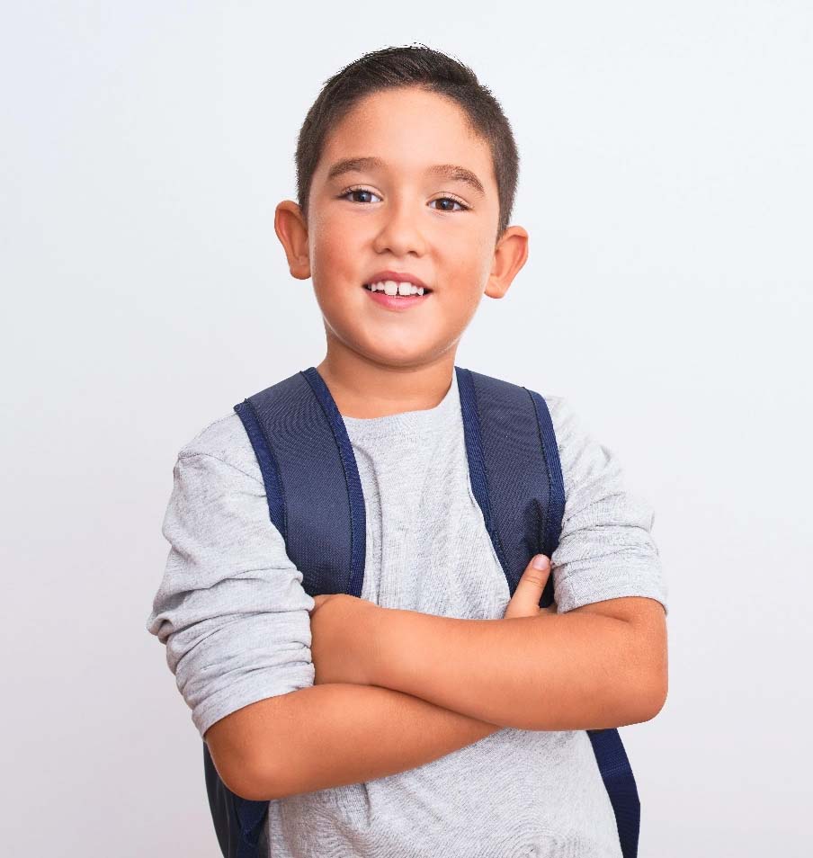 Smiling boy standing with arms crossed wearing a backpack